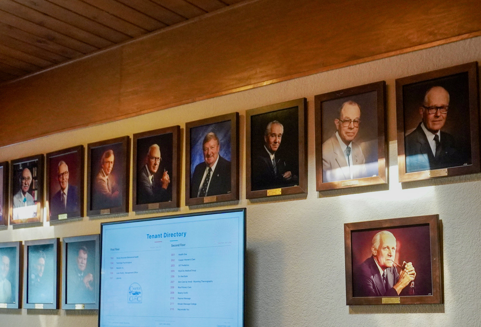 Wall of founding physician portraits beside the tenant directory
